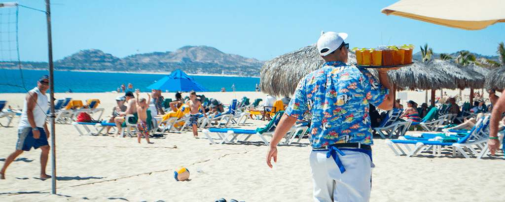 Mesero llevando bebidas en la playa de Club Solaris Cabos